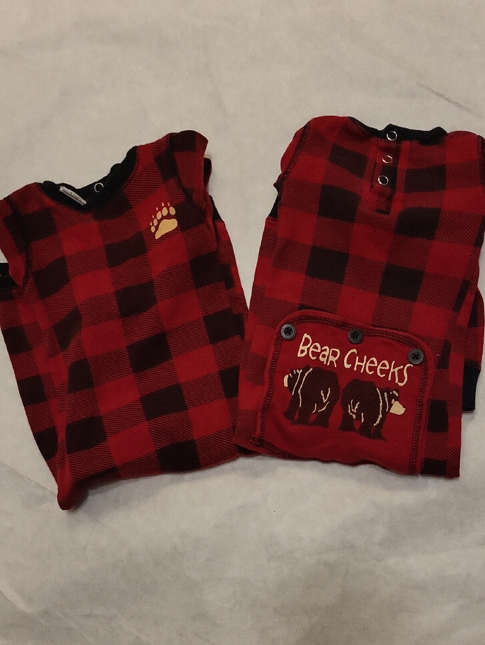 Two red buffalo plaid footless footies with bear cheeks graphic